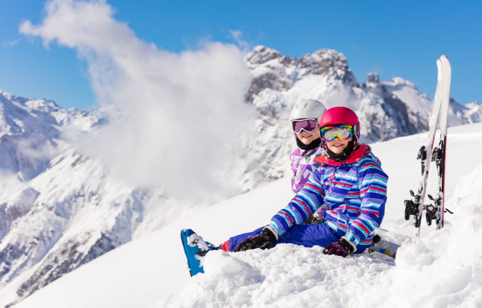 Enfants assis dans la neige avec paysage de montagne