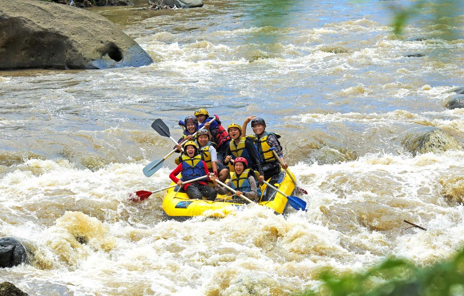 Un groupe de jeunes en rafting sur un torrent avec des rapides
