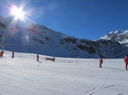 Skieurs sur un téléski avec le soleil qui disparait derrière la montagne