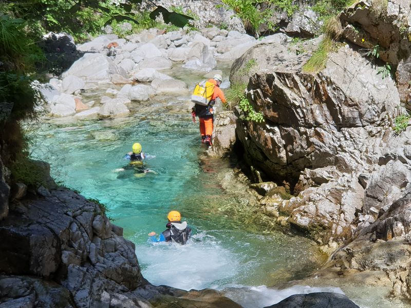 Deux élèves dans un canyon sortant d\'une vasque d'eau claire derrière leur guide