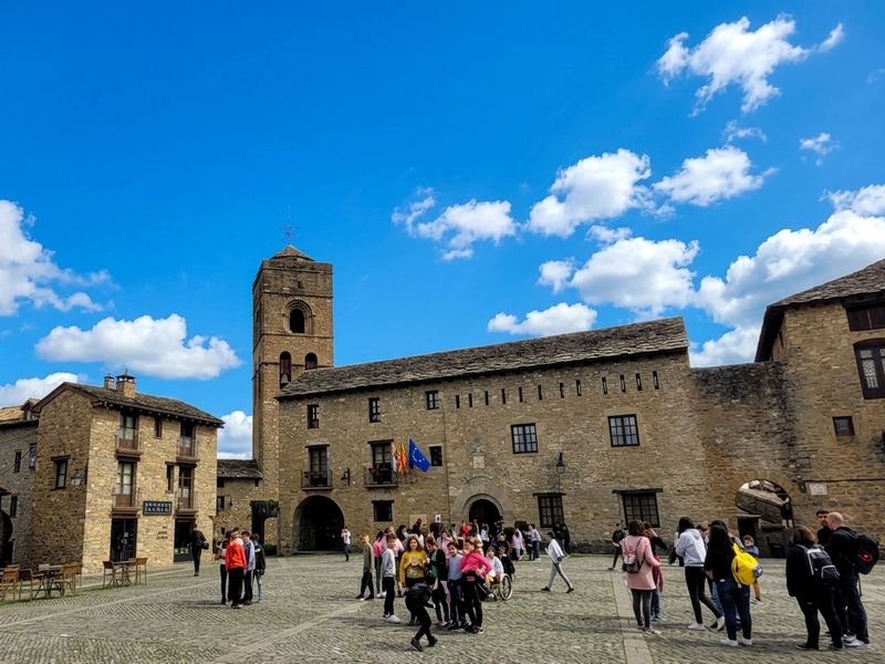 groupe d\élèves sur la plaza mayor d\'Ainsa. Vue sur la mairie et l\église avec un beau ciel bleu
